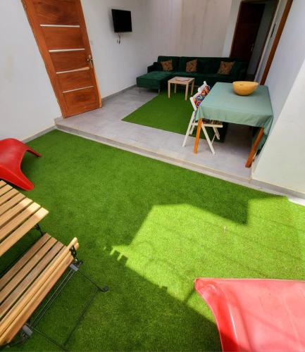 Iknews Appart Dakar في Kammba: غرفة معيشة بها عشب أخضر وطاولة وأريكة