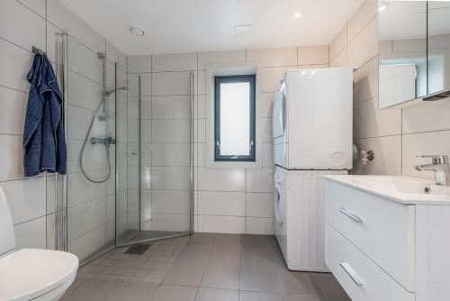 a white bathroom with a shower and a refrigerator at JECI Apartment in Kjeller Lillestrøm - New, Modern and Central in Lillestrøm
