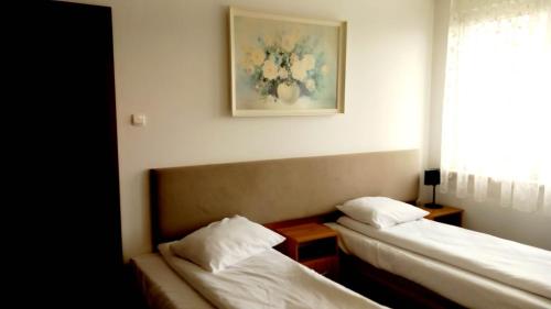 a room with two beds and a picture on the wall at Hotel i Restauracja 13 Smaków in Częstochowa