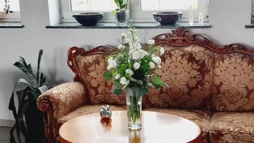 a vase of flowers sitting on a table on a couch at Hotel i Restauracja 13 Smaków in Częstochowa