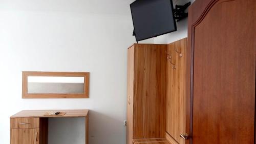 a room with a tv and a wooden cabinet at Hotel i Restauracja 13 Smaków in Częstochowa