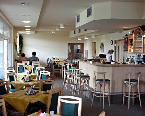 a restaurant with tables and chairs and a bar at Hotel Smaragd in Prague