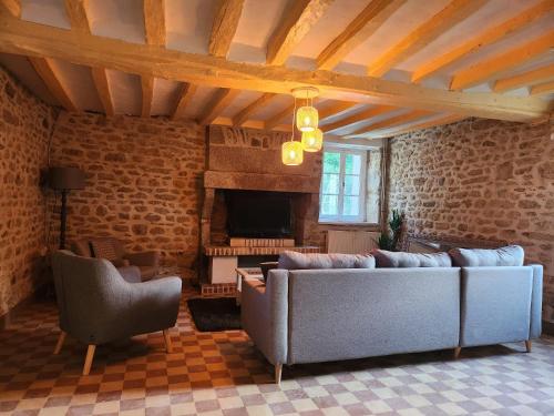 sala de estar con 2 sofás y chimenea en Le Clos Loret en Saint-Germain-du-Corbéis