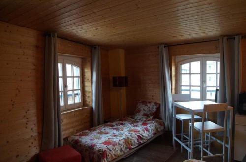 um quarto com uma cama, uma mesa e janelas em Agapi em Le Puy-en-Velay