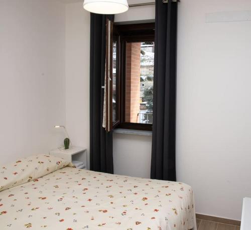 a bed in a room with a window and a bedspread at Casa Valentin in Monforte dʼAlba