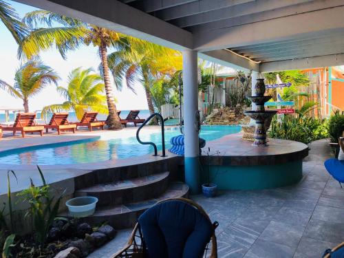 a swimming pool with palm trees and a resort at Coral Cove Inn in Seine Bight Village