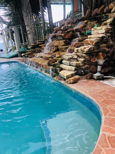 a swimming pool with a waterfall and a stone wall at Coral Cove Inn in Maya Beach