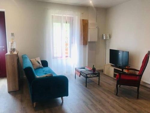 Chez Gaston في شامبون-سورلاك: غرفة معيشة مع أريكة زرقاء وتلفزيون