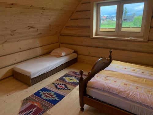 a bedroom with two beds in a log cabin at Zagroda na Borach - Domek in Jabłonka