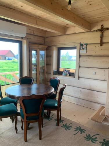a dining room with a wooden table and chairs at Zagroda na Borach - Domek in Jabłonka