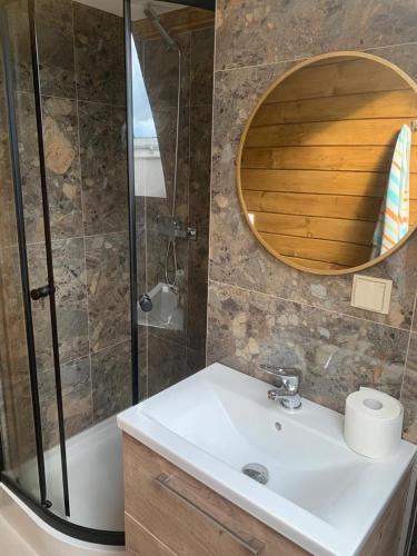 a bathroom with a sink and a shower and a mirror at Zagroda na Borach - Domek in Jabłonka