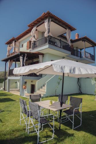 a table and chairs with an umbrella in front of a building at BS Village in Metamorfosi