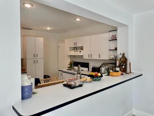 a kitchen with white cabinets and a white counter top at Queen's Tropical Garden View Room in Palmetto Bay