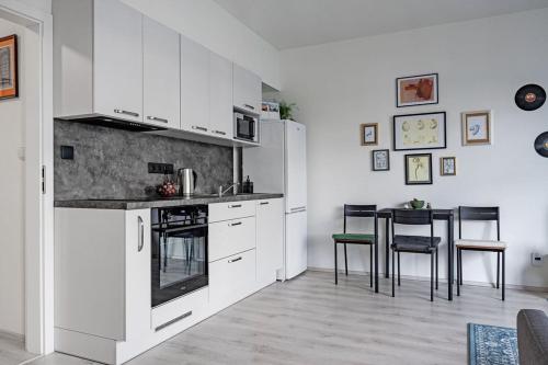 cocina con armarios blancos, mesa y sillas en Nové Sady Olomouc en Olomouc