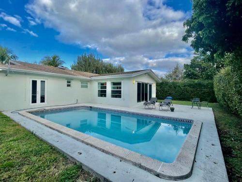 a swimming pool in front of a house at Queen's Tropical Garden View Room in Palmetto Bay