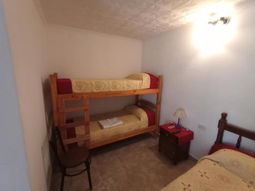 Mały pokój z 2 łóżkami piętrowymi i krzesłem w obiekcie Trujui Host w mieście Termas de Río Hondo