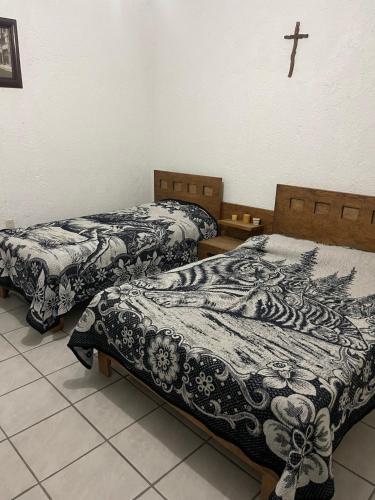2 camas en una habitación con una cruz en la pared en Hermosa Casa Campestre Para 12 Personas, en Los Sauces