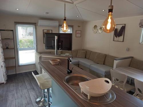 a kitchen and living room with a sink and a couch at Mobil-home FO 88 à VIAS in Vias