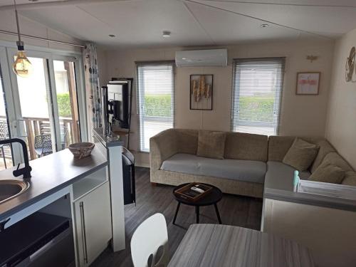 a living room with a couch and a kitchen at Mobil-home FO 88 à VIAS in Vias
