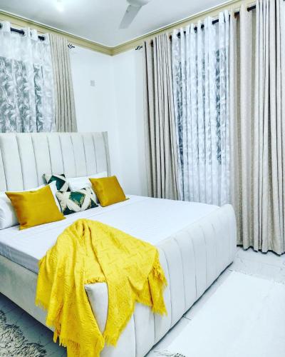 een slaapkamer met een wit bed met een gele deken erop bij Airbn b Mombasa Bamburi in Mombasa