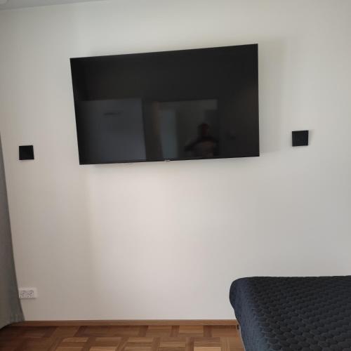 a flat screen tv on a white wall with a couch at Esplanad Suites in Mariehamn