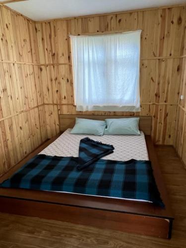 a bed in a wooden room with a window at База відпочинку Енергія in Rudnya Peskovskaya