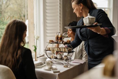 a woman holding a tray of food on a table at The Roseate Villa Bath in Bath