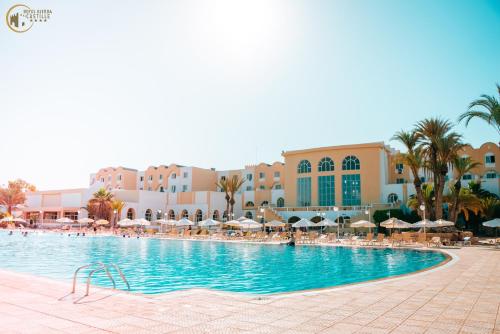 einen Pool mit Stühlen und Sonnenschirmen in einem Resort in der Unterkunft Djerba Castille in Aghīr
