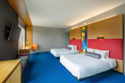 a hotel room with two beds and a tv at Aloft San Jose Hotel, Costa Rica in San José
