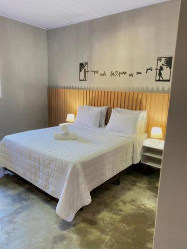 a bedroom with a large bed with white sheets at Casa Para Temporada Residência Silva in Pirenópolis