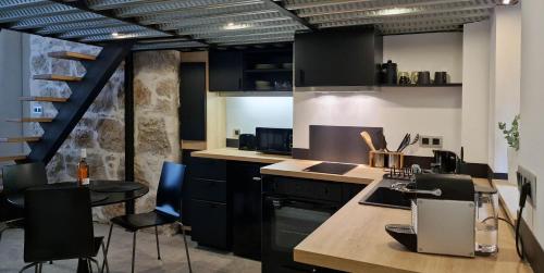 une cuisine avec des armoires noires, une table et des chaises dans l'établissement Très joli loft au cœur de Nice, à Nice