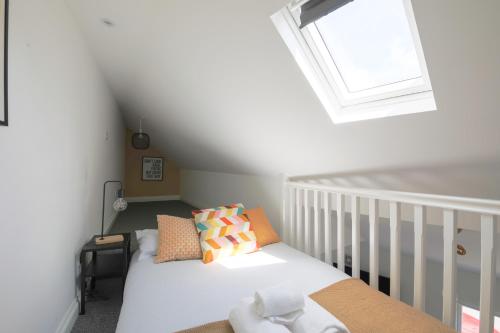een kleine slaapkamer met een bed en een raam bij StayRight Cosy Mezzanine Flat in Vibrant Area - Walking Distance to Central Cardiff in Cardiff
