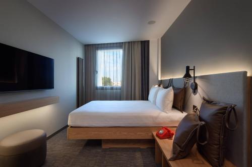 a hotel room with a bed and a flat screen tv at Moxy Lisbon City in Lisbon