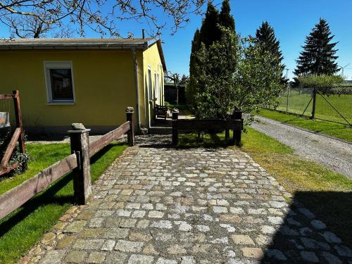 a stone walkway leading to a small yellow building at Klättes Ferienwohnung mit Garten in Zagelsdorf