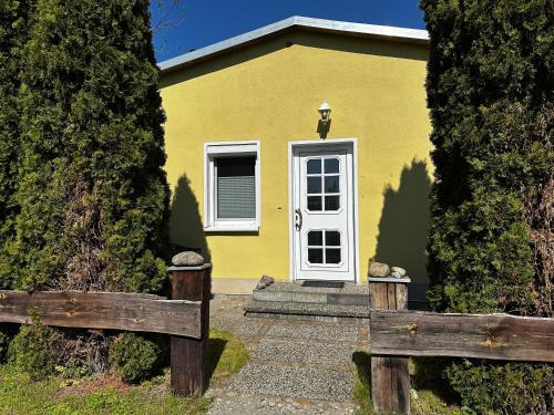 a yellow house with a white door and two wooden fences at Klättes Ferienwohnung mit Garten in Zagelsdorf