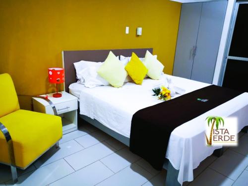 Habitación de hotel con cama y silla amarilla en Apartamento Vacacional Vista Verde, en Tarapoto