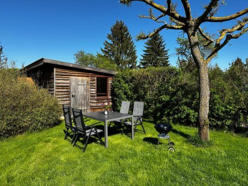a table and chairs in the grass next to a cabin at Klättes Ferienwohnung mit Garten in Zagelsdorf
