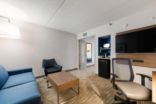 a living room with a couch and chairs and a tv at Holiday Inn Express Naperville by IHG in Naperville