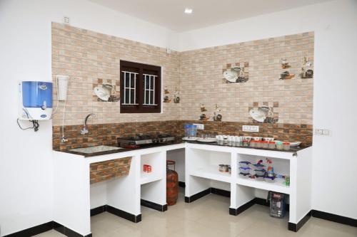 a kitchen with white counters and a brick wall at JDP Villa 2 Bhk House in Ooty