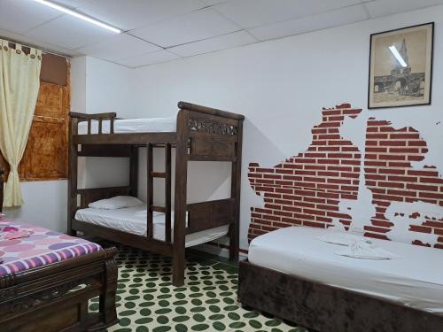 a room with two bunk beds and a brick wall at Hostal Casa Lara in Cartagena de Indias