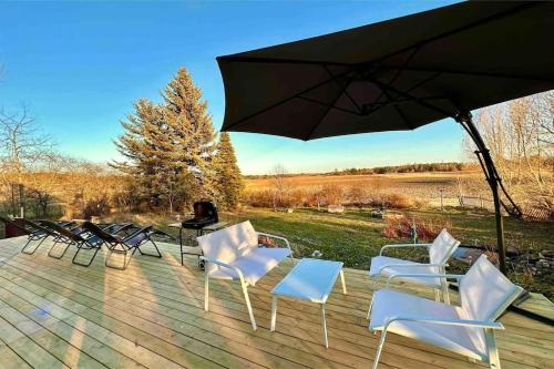 a group of chairs and an umbrella on a deck at Modernt & rymligt sommarhus på landet- Bubbelpool in Eskilstuna