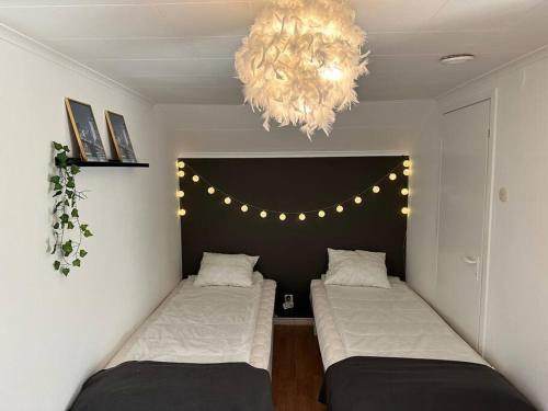 a room with two beds and a chandelier at Modernt & rymligt sommarhus på landet- Bubbelpool in Eskilstuna