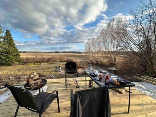 a deck with chairs and a table with a view of a field at Modernt & rymligt sommarhus på landet- Bubbelpool in Eskilstuna