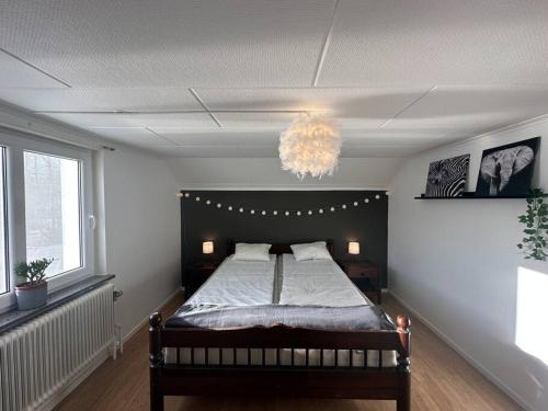 a bedroom with a bed and a chandelier at Modernt & rymligt sommarhus på landet- Bubbelpool in Eskilstuna