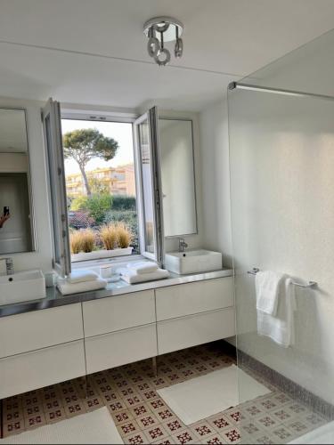 une salle de bain blanche avec deux lavabos et un miroir dans l'établissement La Suite 68 Bandol avec jardin et parking privatif, à Bandol