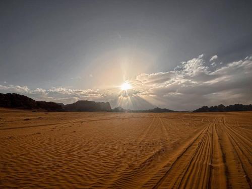 a desert with the sun shining in the sky at Scoop Rum in Wadi Rum