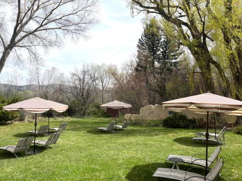 eine Gruppe von Stühlen und Sonnenschirmen auf einem Hof in der Unterkunft Hacienda Del Sol in Taos