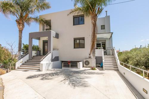 a white house with palm trees in front of it at Crystal Waves lux villa-Homeleader in Chania Town