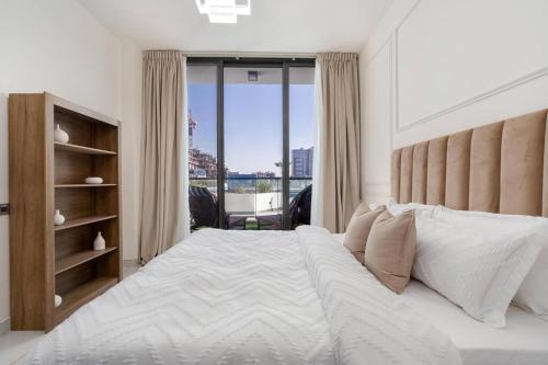 a bedroom with a large white bed with a large window at Modern one-bedroom in Arjan - Dubaï in Dubai