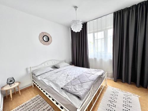 Turnu MăgureleにあるCozy Apartmentのベッドと窓のある白い寝室